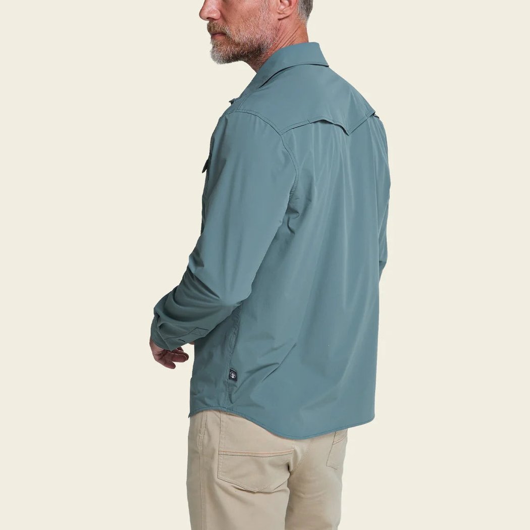 Side view of the Howler Brothers Emerger Tech Longsleeve in Stormy Sea on a model wearing khaki pants against a plain background.