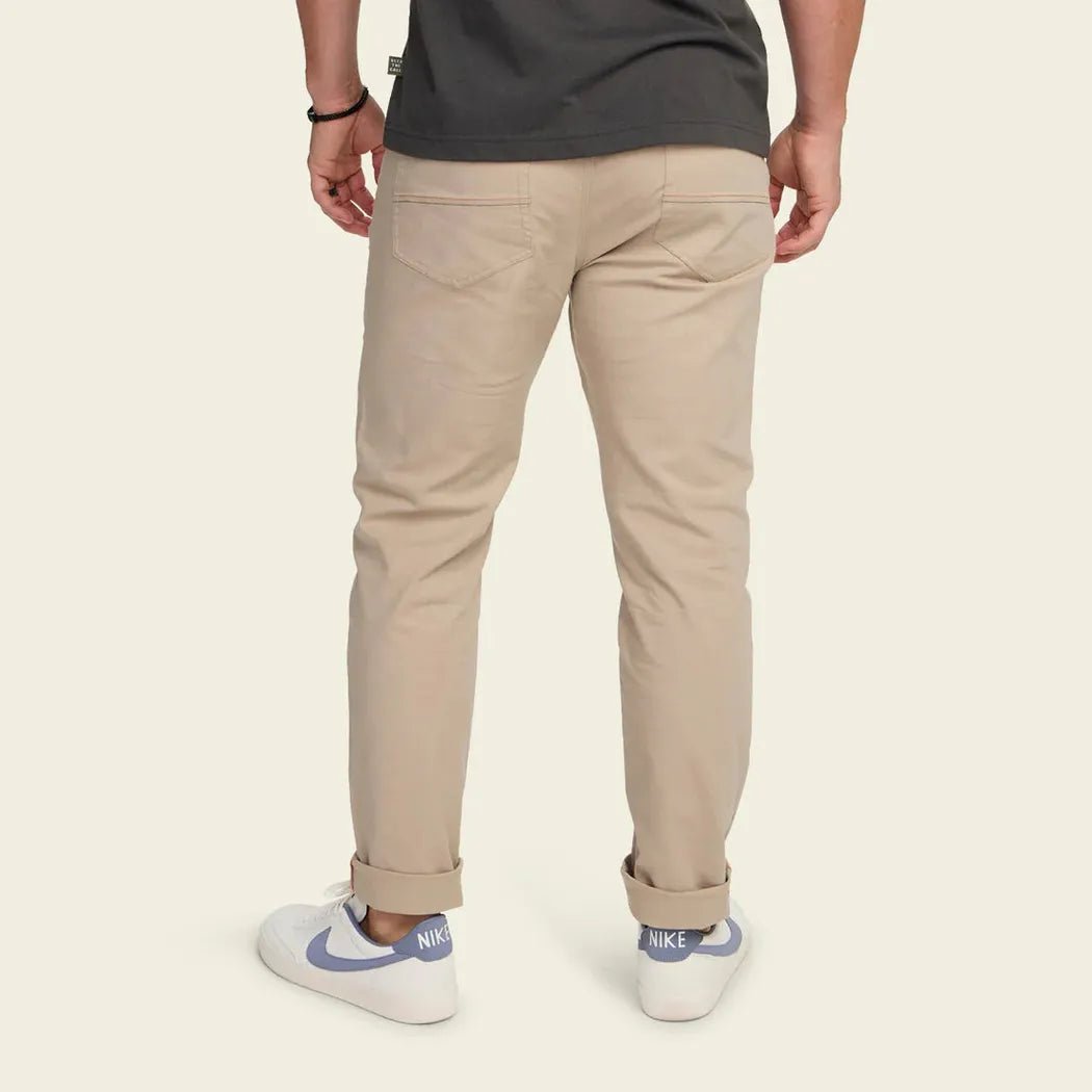 Back view of the Howler Brothers Frontside 5-Pocket Pants in Faded Khaki on a model wearing white Nike sneakers against a plain background.