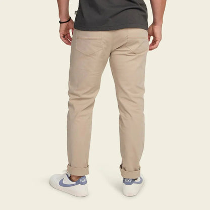 Back view of the Howler Brothers Frontside 5-Pocket Pants in Faded Khaki on a model wearing white Nike sneakers against a plain background.
