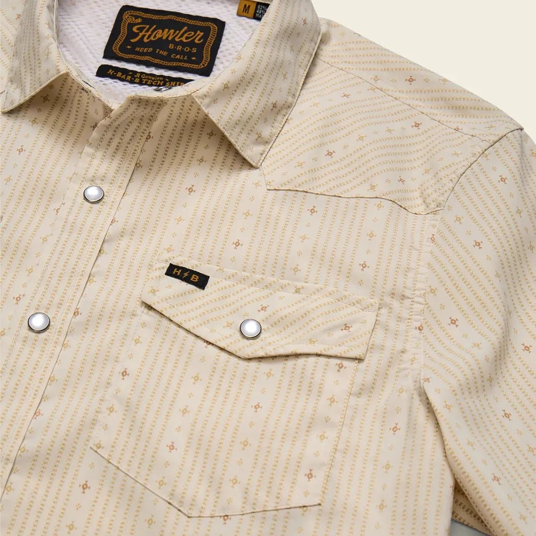A close-up of the Howler Brothers Men's H Bar B Tech Longsleeve in Supernova Stripe : Leche showing the chest pocket and button placket against a neutral background.