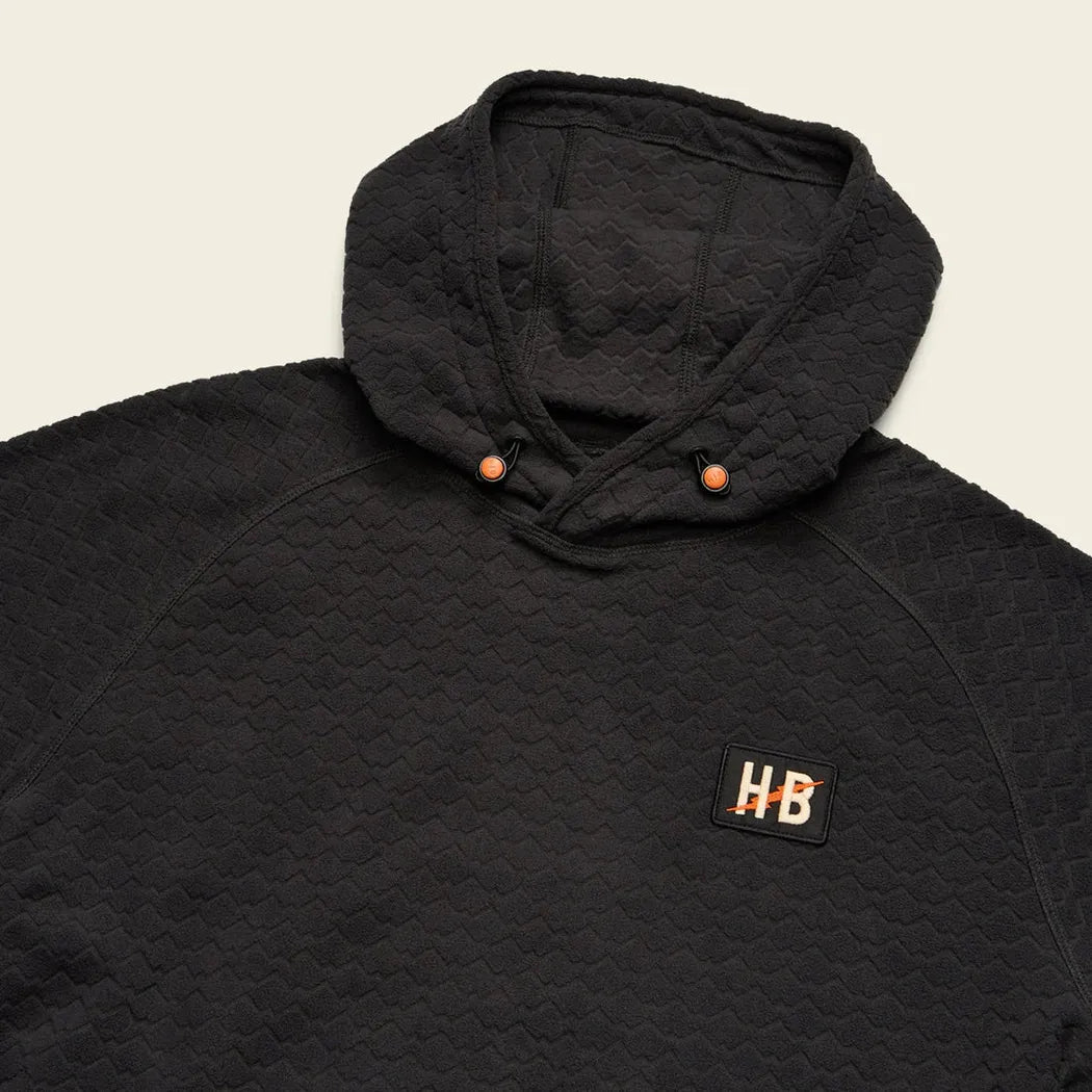 A close-up of the Howler Brothers Men's Palo Duro Fleece Hoodie in Antique Black showing the hood and "HB" patch against a light background.