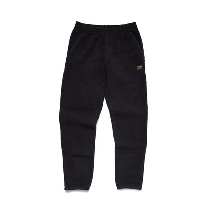 Side view of the Howler Brothers Men's Pelusa Fleece Pants in Pine Needle showing the small patch on the right thigh against a white background.