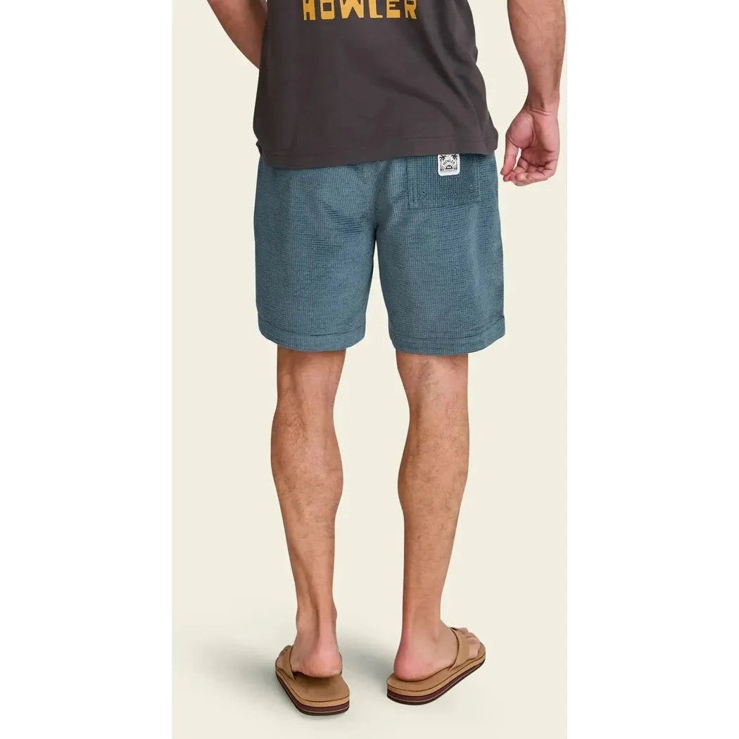 Back view of the Howler Brothers Men's Pressure Drop Cord Shorts in Grid : Blue Mirage, showing the model wearing them and brown flip flops against a light background.