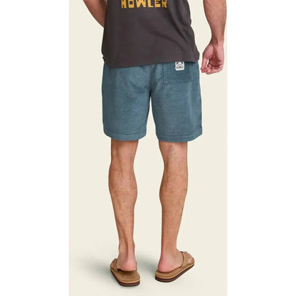 Back view of the Howler Brothers Men's Pressure Drop Cord Shorts in Grid : Blue Mirage, showing the model wearing them and brown flip flops against a light background.