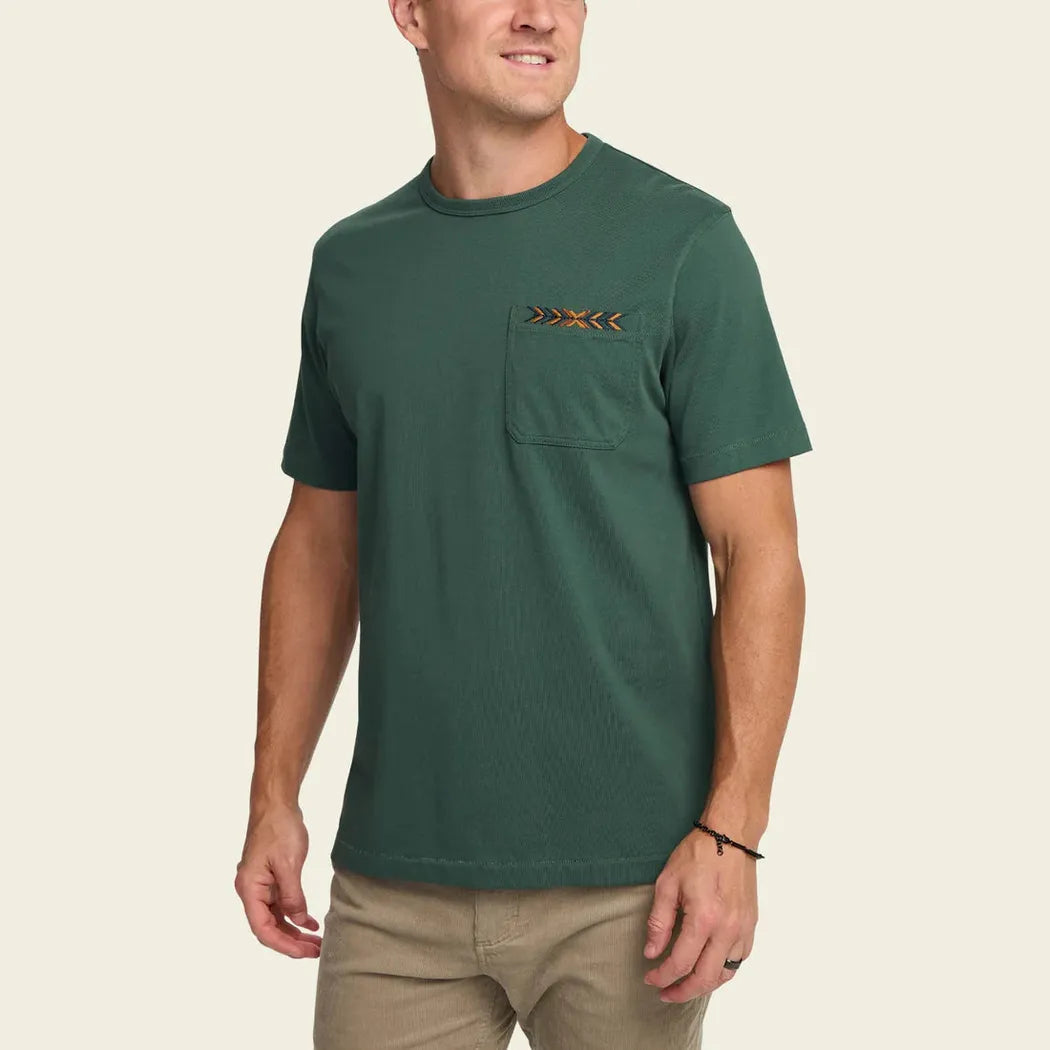 A front view of the Howler Brothers Men's Spectrum Pocket T in Bone White on a model wearing khaki pants against a plain background.