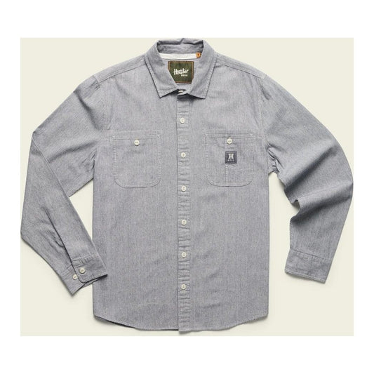 A front view of the Howler Brothers Men's Tallier Work Shirt in Hickory Stripe Chambray with two chest pockets and a small logo patch, laid flat against a light background.
