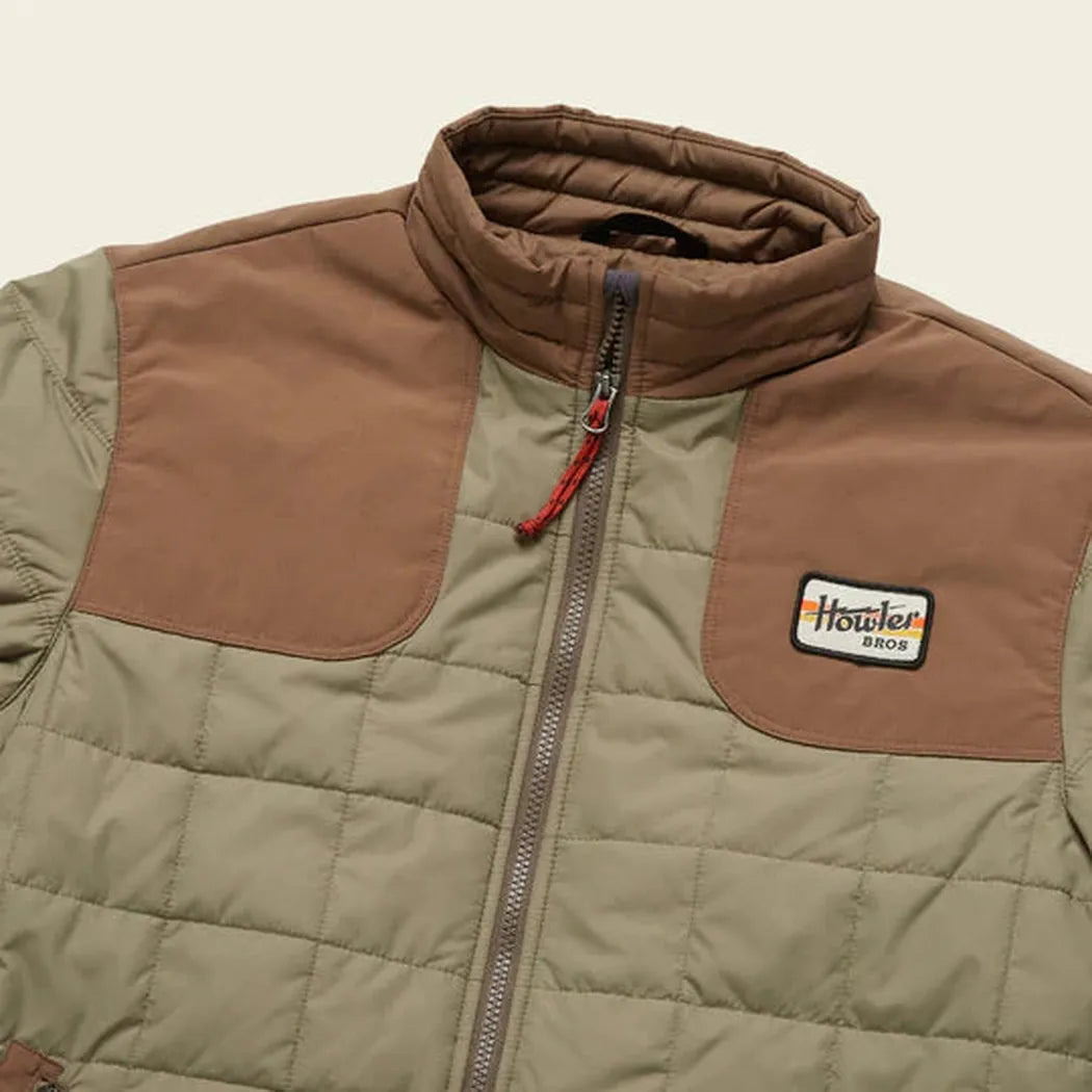 A close-up of the Howler Brothers Merlin Jacket in Mountain Green and Teak with a front zipper and logo patch.