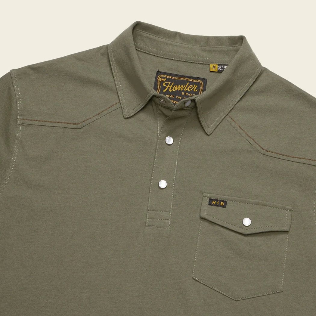 A close-up of the Howler Brothers Ranchero Polo in Cadet color showing the chest pocket and button placket against a neutral background.