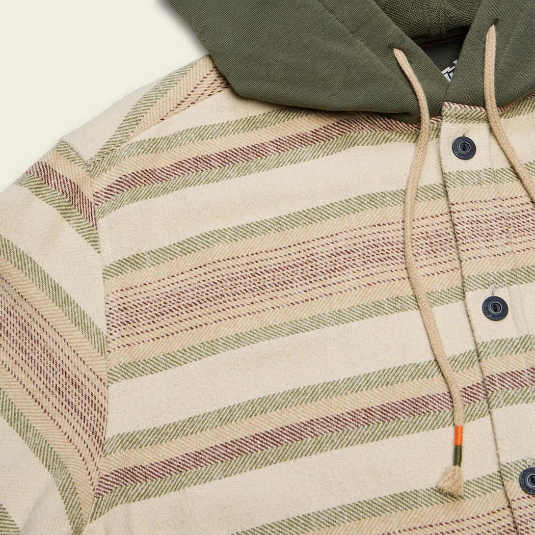 A close-up of the Howler Brothers Salvo Hooded Blanket Flannel in Pathway Stripe Dawn showing the hood and button placket against a neutral background.
