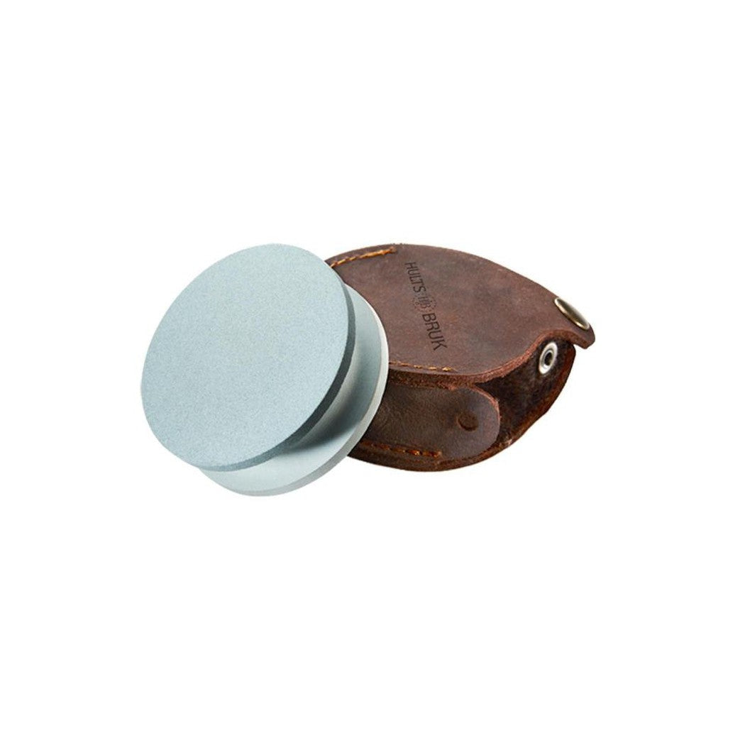 A top-down view of the Hults Bruk Grinding Stone 180/600 with its brown leather case on a white background.
