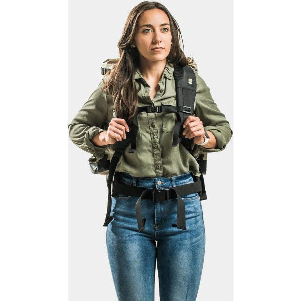 A woman wearing the IceMule Coolers Boss (30L) in Sand stands against a plain white background.