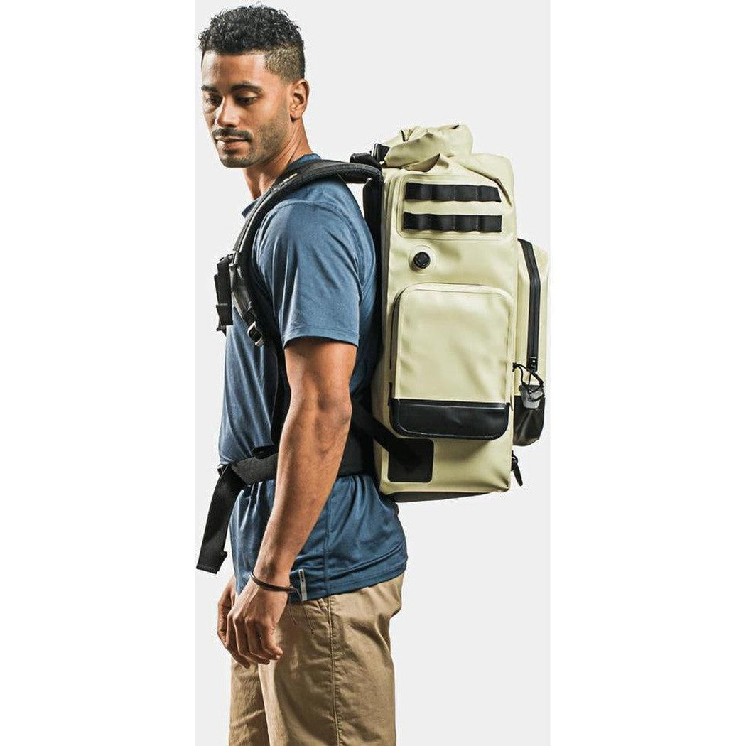 Side view of the IceMule Coolers Boss (30L) in Sand showing the front pocket and model wearing it against a white background.