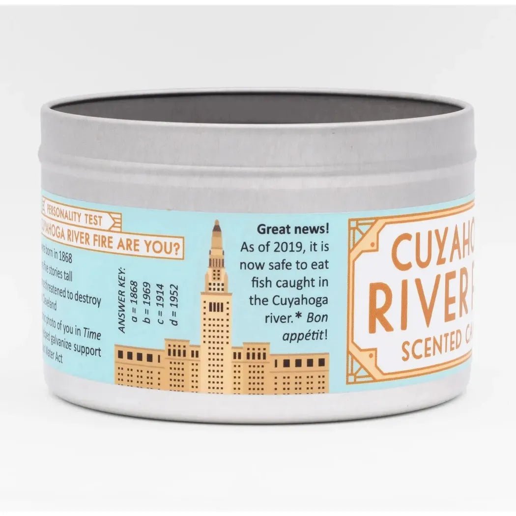 A round white candle tin with "Cuyahoga River" on the label and a city skyline illustration.