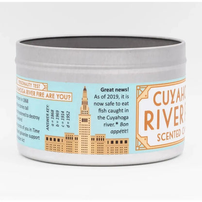 A round white candle tin with "Cuyahoga River" on the label and a city skyline illustration.