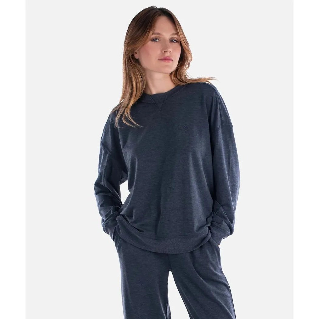 A model wearing the Jetty Women's Rosewood Crewneck Sweatshirt in Navy stands against a plain white background.