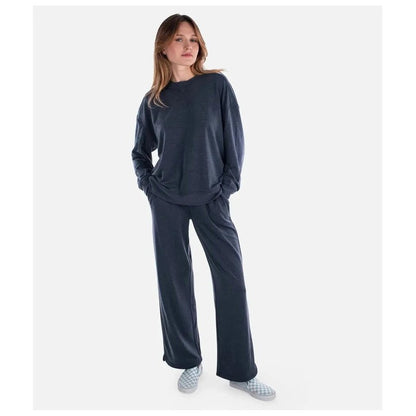 A woman wearing the Jetty Women's Rosewood Crewneck Sweatshirt in Navy stands against a plain white background.