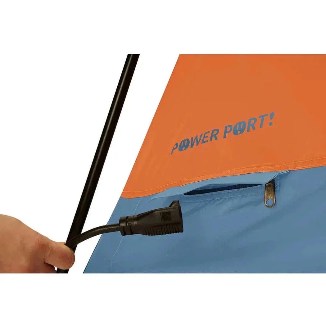 A hand holds a black pole near the orange and blue Eureka! Copper Canyon LX 6 tent with a power port visible.