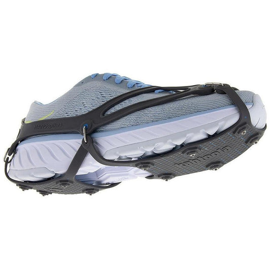 Side view of the Kahtoola NANOspikes Footwear Traction in Black showing the metal spikes and black straps on a light blue running shoe against a white background.