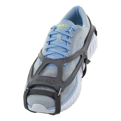 A side view of the Kahtoola NANOspikes Footwear Traction on a light blue running shoe with a black traction device, against a white background.