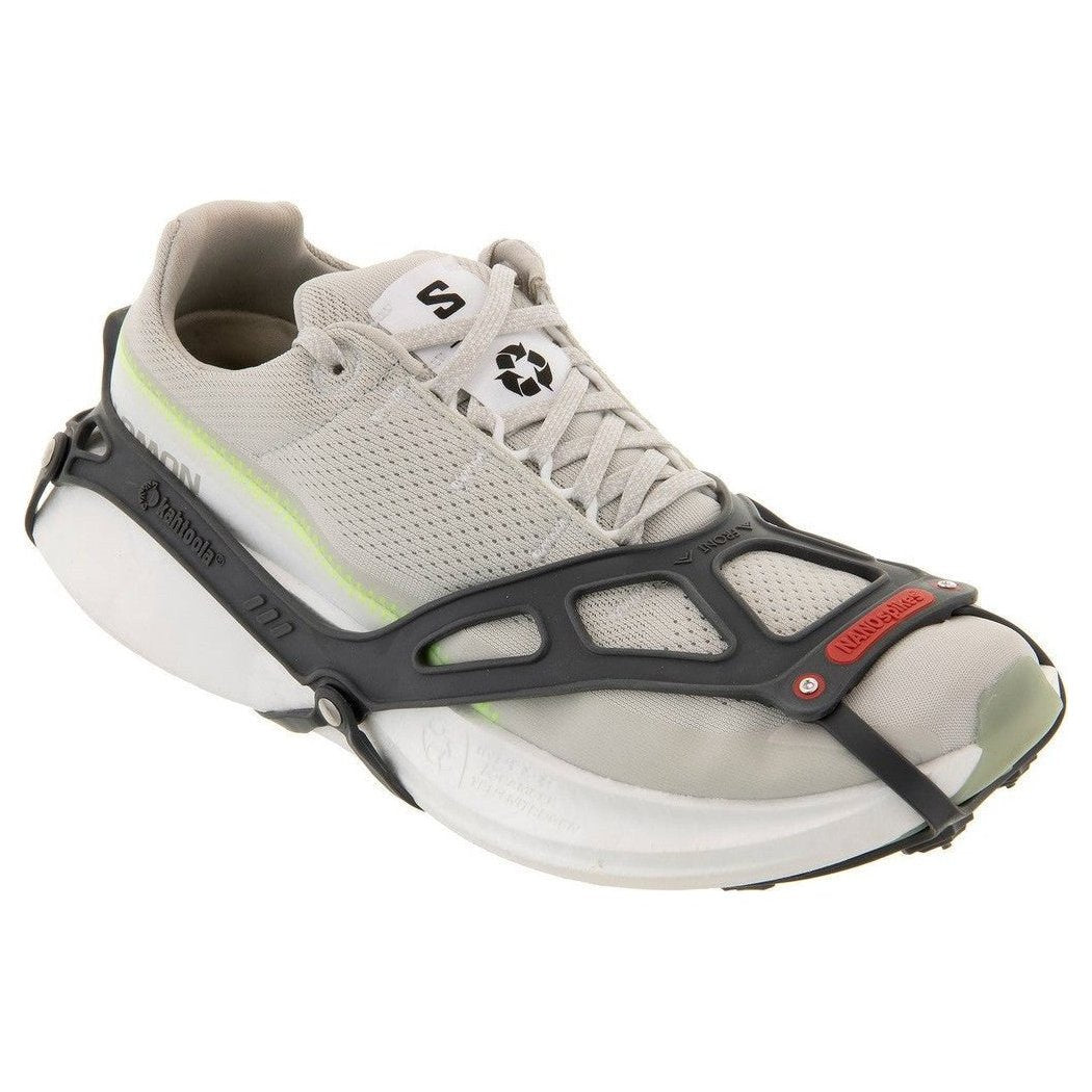 Side view of the Kahtoola NANOspikes Footwear Traction in Black showing the black traction device on a light gray sneaker against a white background.