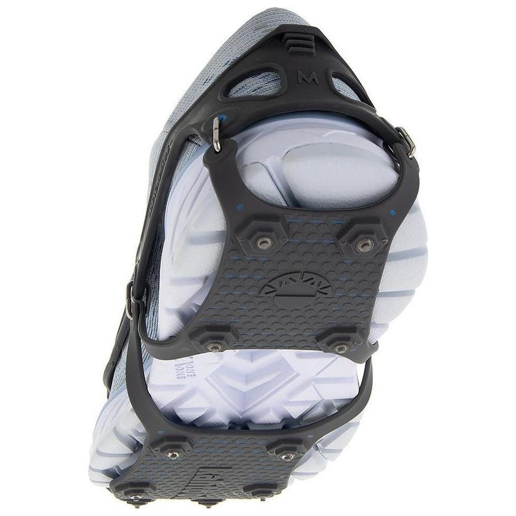 A close-up of the Kahtoola NANOspikes Footwear Traction in Black, showing the black metal spikes and straps on a white shoe sole against a white background.