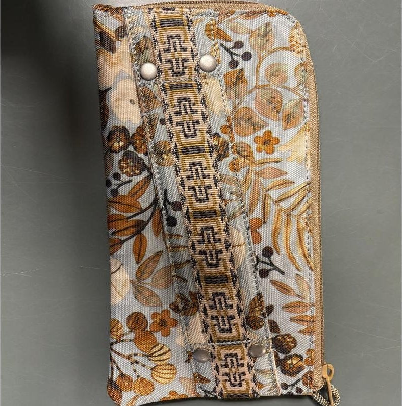 A top-down view of the Kavu Clutch Case in Frosty Foliage showing the zipper and decorative pattern against a gray background.