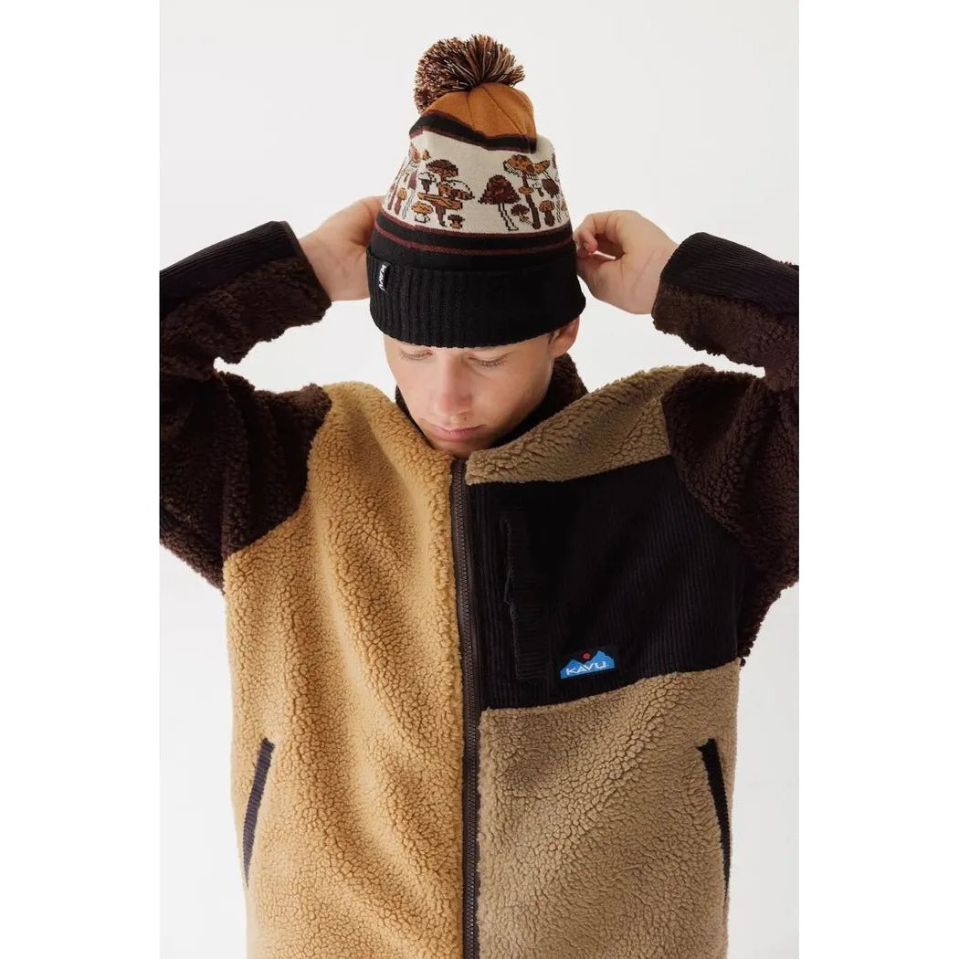 A model wears the Kavu Herschel Mushroom Patch hat with a pom pom, against a plain white background.