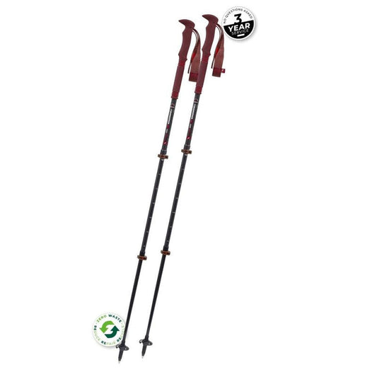 Two Komperdell Carbon PRO ZERO Compact trekking poles with red grips stand upright against a white background, showing their adjustable sections and sharp tips.