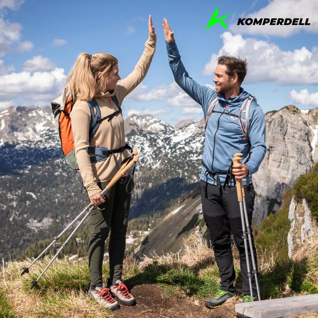 A man and woman high-five while hiking with Komperdell Explorer Zero Cork trekking poles against a mountain backdrop.