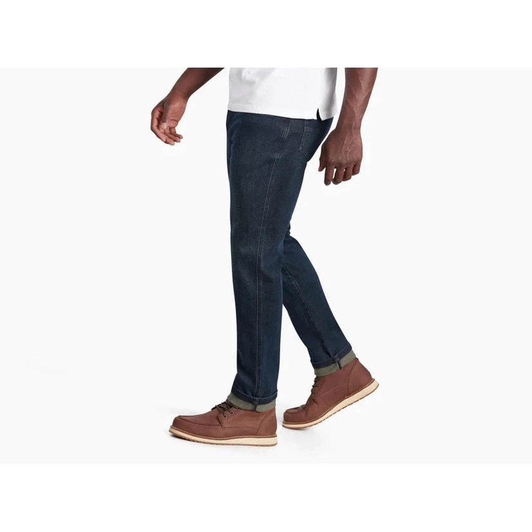 Side view of the Kuhl Men's Kuhl Denim in Midnight showing the rolled cuffs and brown boots against a white background.