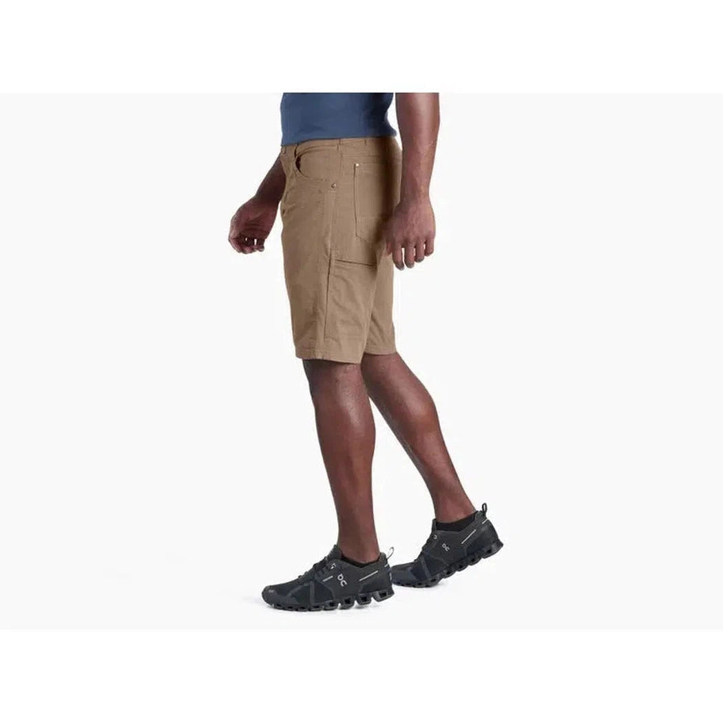Side view of the Kuhl Men's Radikl Short Inseam in Dark Khaki on a model wearing black athletic shoes against a white background.