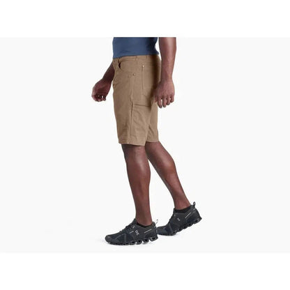 Side view of the Kuhl Men's Radikl Short Inseam in Dark Khaki on a model wearing black athletic shoes against a white background.