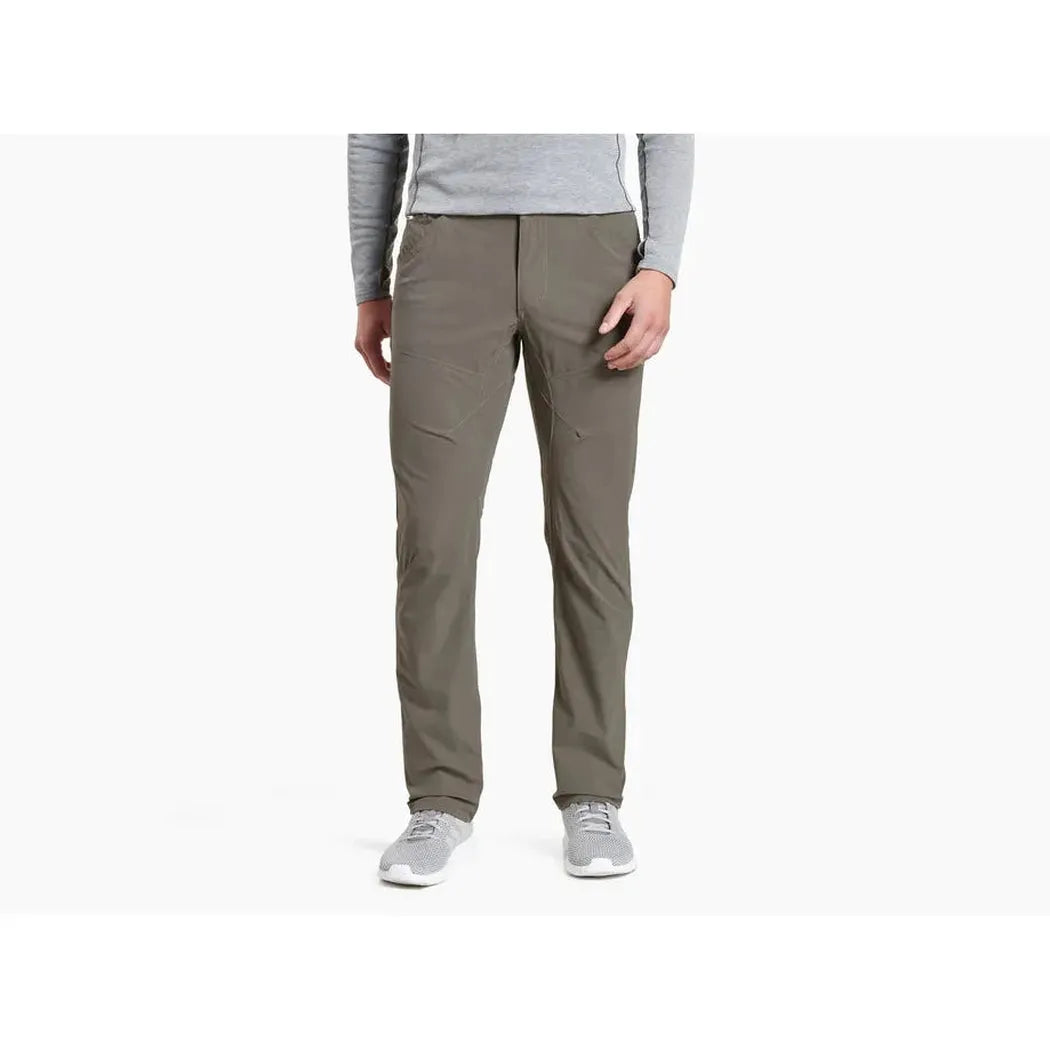 A front view of the Kuhl Men's Silencr Pant in Storm Khaki on a model wearing light gray shoes against a white background.