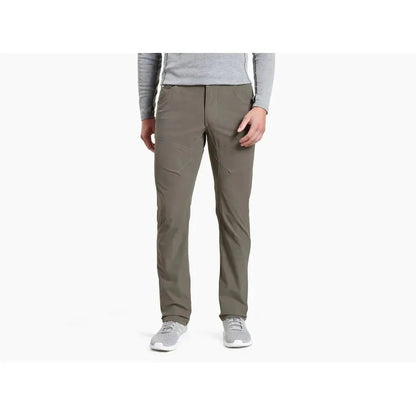 A front view of the Kuhl Men's Silencr Pant in Storm Khaki on a model wearing light gray shoes against a white background.