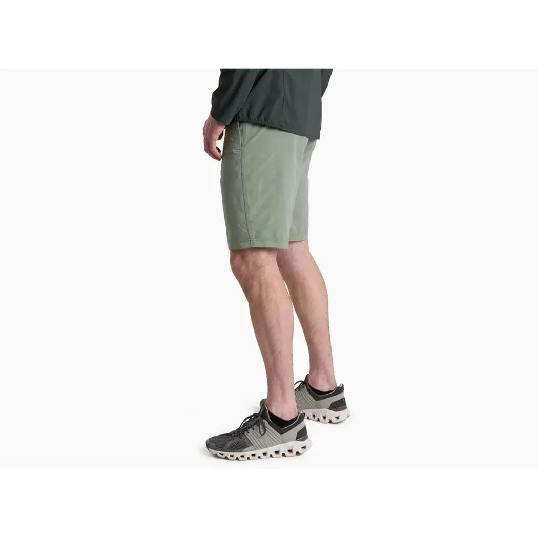 Side view of the Kuhl Men's Upriser Short in Slate Green on a model wearing black and gray sneakers against a white background.
