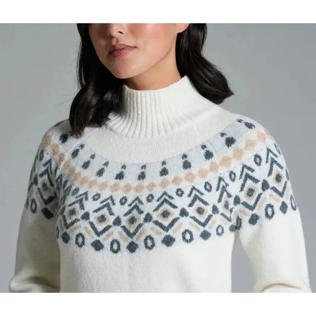 A front view of the Kuhl Women's Alpina Sweater in Alpine White showing the patterned yoke and turtleneck against a gray background.