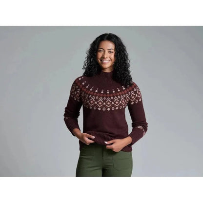 A woman wearing the Kuhl Women's Alpina Sweater in Alpine White stands against a gray background.