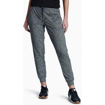 A front view of the Kuhl Women's Bliss Joggr in Dark Heather, showing the elastic waistband and cuffed ankles on a model wearing black Nike sneakers against a white background.