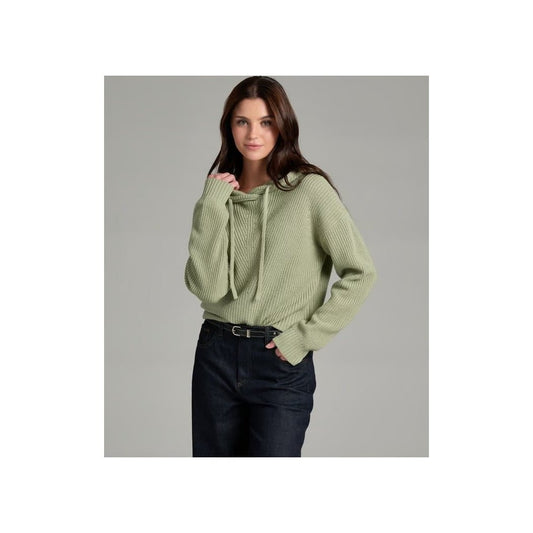 A front view of the Kuhl Women's Fireside Sweater Hoody in Sea Crest on a model wearing dark jeans against a gray background.