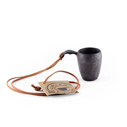 A charcoal Kupilka 5 Shot Cup with a leather strap and tag, shown from a side angle against a white background.