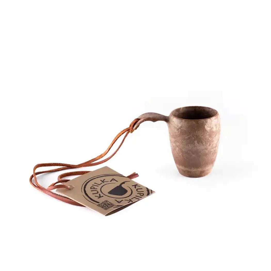 A side view of the Kupilka 5 Shot Cup in Black showing the leather strap and tag against a white background.