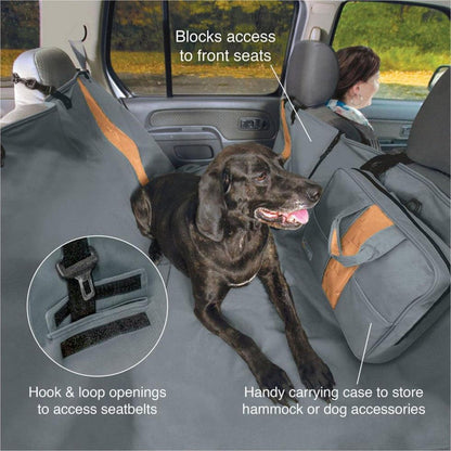 A black dog lies on a Charcoal Kurgo Wander Hammock in a car, with a woman in the front seat and a carrying case attached to the back seat.