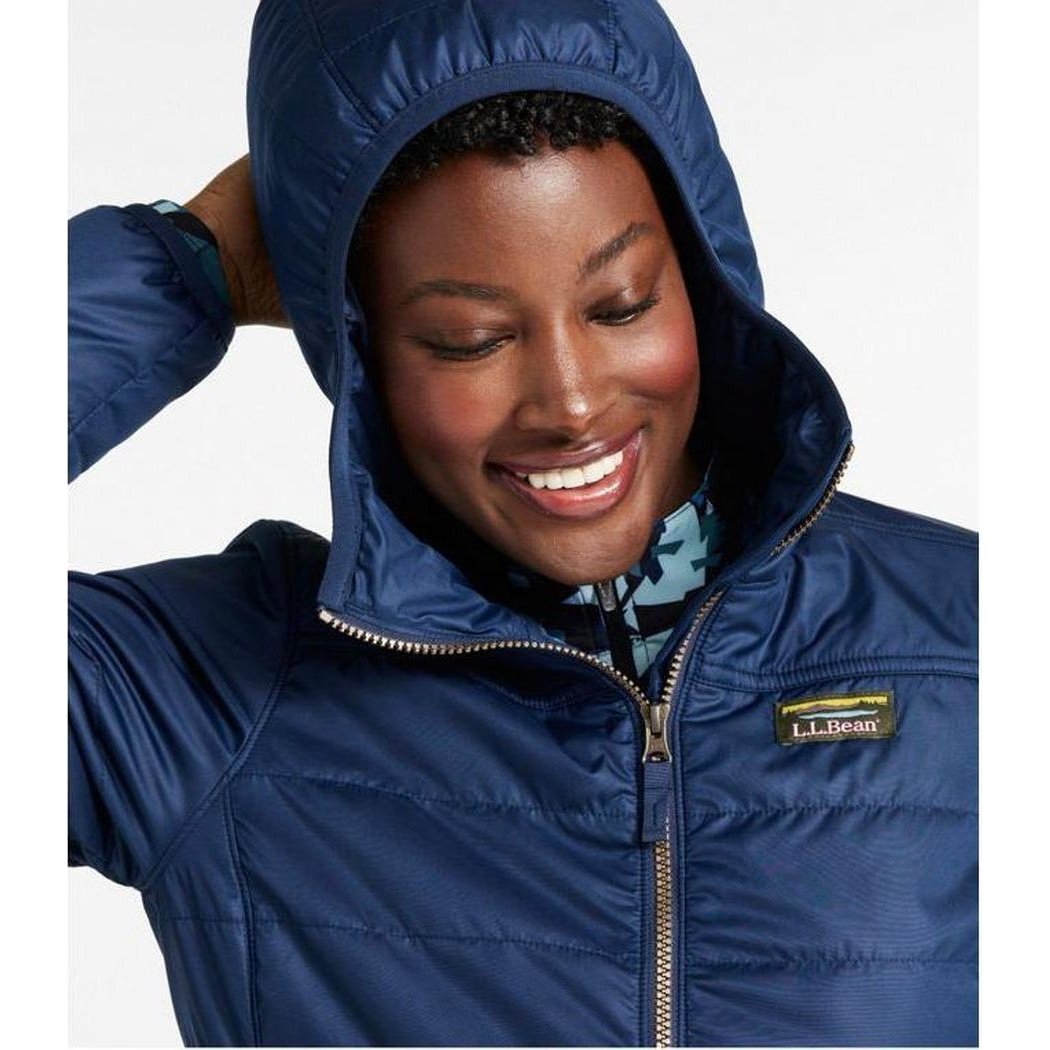 A woman wearing the Nautical Navy L.L.Bean Women's Mountain Classic Puffer Coat with the hood up, smiling at the camera against a white background.