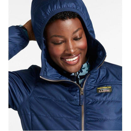 A woman wearing the Nautical Navy L.L.Bean Women's Mountain Classic Puffer Coat with the hood up, smiling at the camera against a white background.