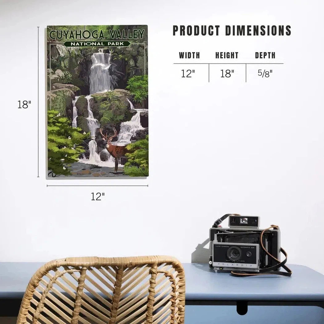 A 12x18 Deer and Falls Cuyahoga Valley National Park wood sign hangs on a wall above a desk with a camera and chair.