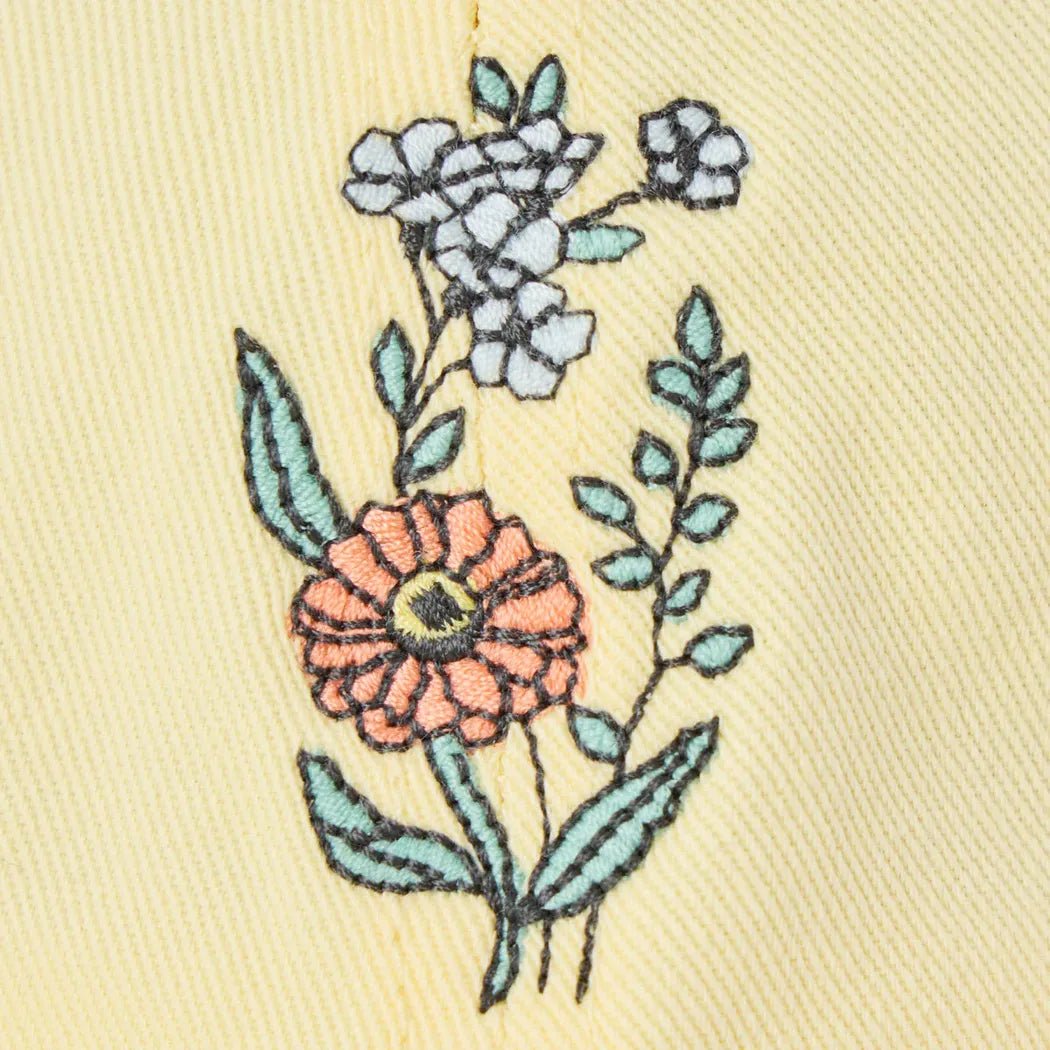 A close-up of the Life is Good Adult Unisex Zinnia Bouquet Chillcap in Birch White, showing embroidered flowers on a light background.