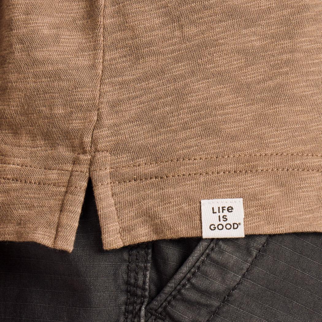 A close-up of the Life is Good Men's Mountain Landscape Short Sleeve Slub Slim Fit Tee in Mushroom Brown, showing the brand tag and stitching on the hem.