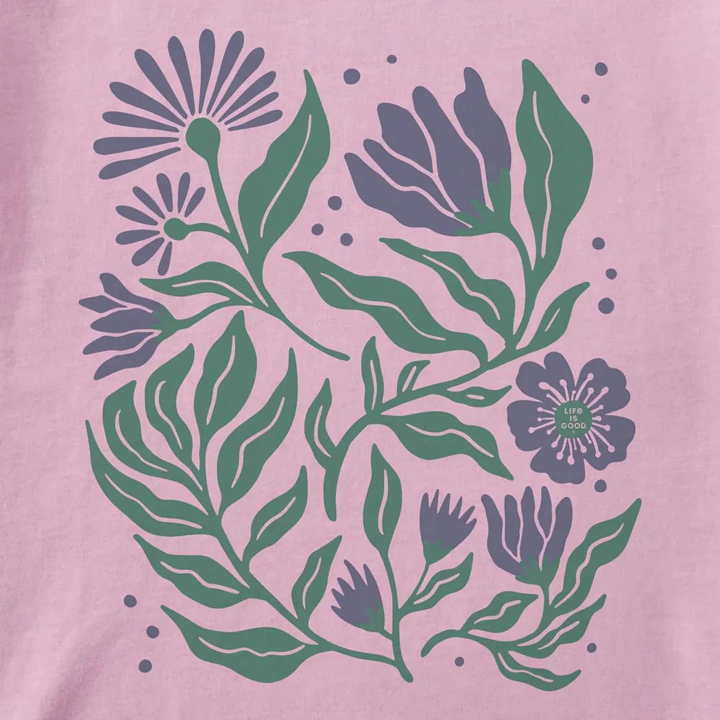 A violet purple Life is Good Women's Array of Flowers Short Sleeve Crusher Tee with green leaves and flowers on a pink background.