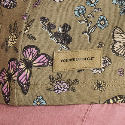 A close-up of the Life is Good Women's Butterfly Garden Pattern Crusher Boxy Tank in Moss Green showing the "Positive Lifestyle" tag and butterfly design.
