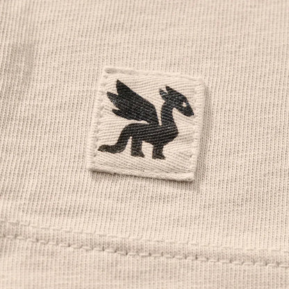 A close-up of the Life is Good Women's Florowl Moon Short Sleeve Crusher Tee in Birch White showing the embroidered dragon logo on the chest.